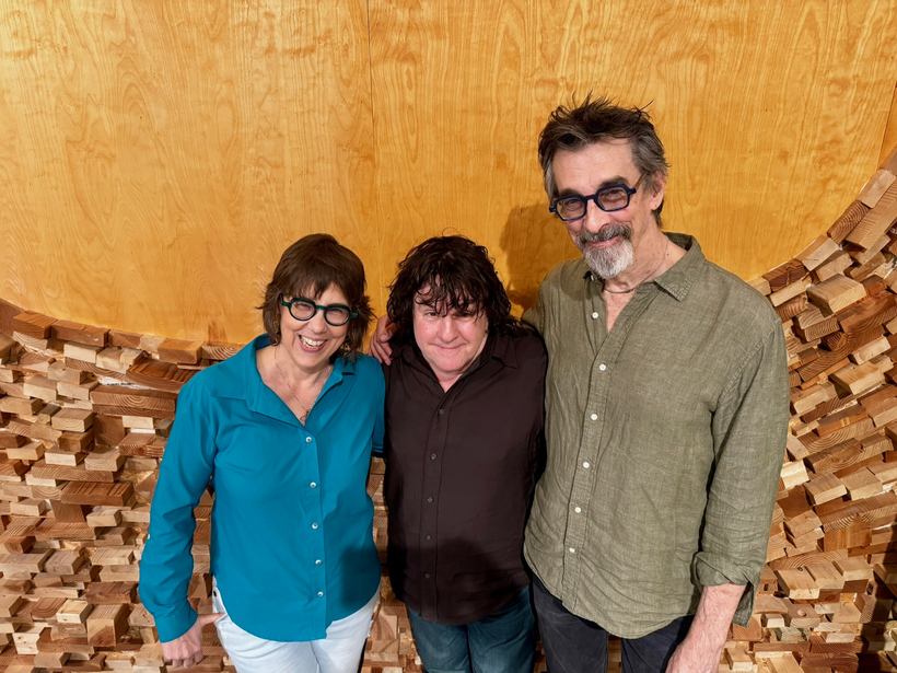 Beth Falcone and Ritt Henn with a fellow musician in front of the studio&rsquo;s wooden wave wall.