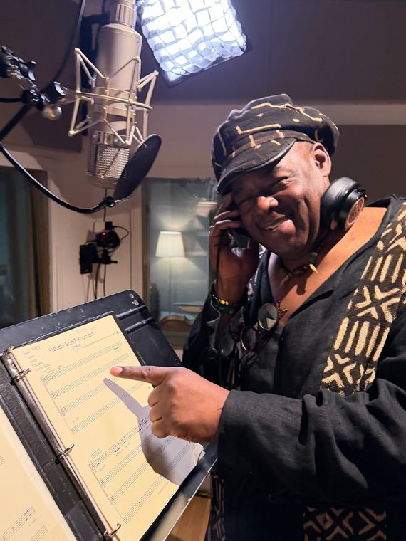 A vocalist grins and points at the Habari Gani? Kuumba! score beneath the vocal mic.