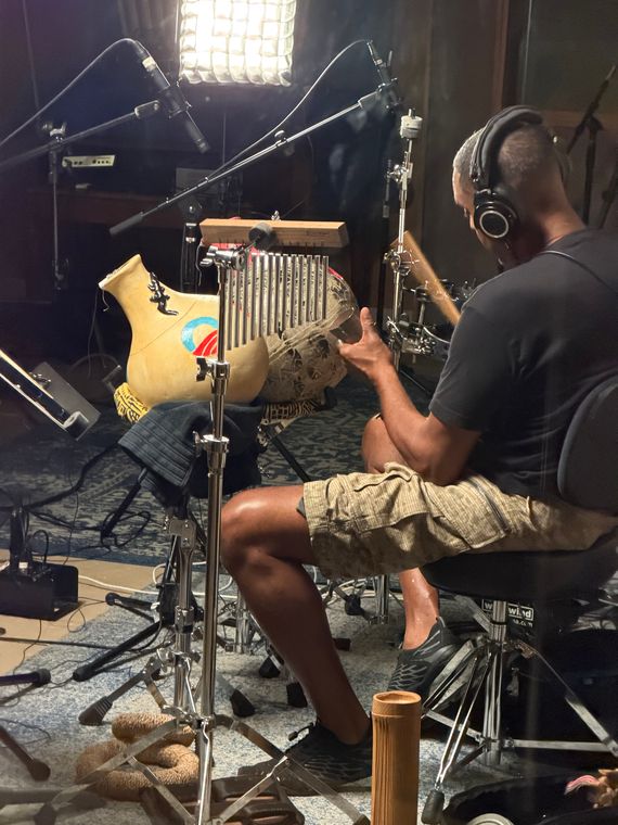 Ronnie Burrage in headphones, playing percussion among clay pot drums and a bar chime.