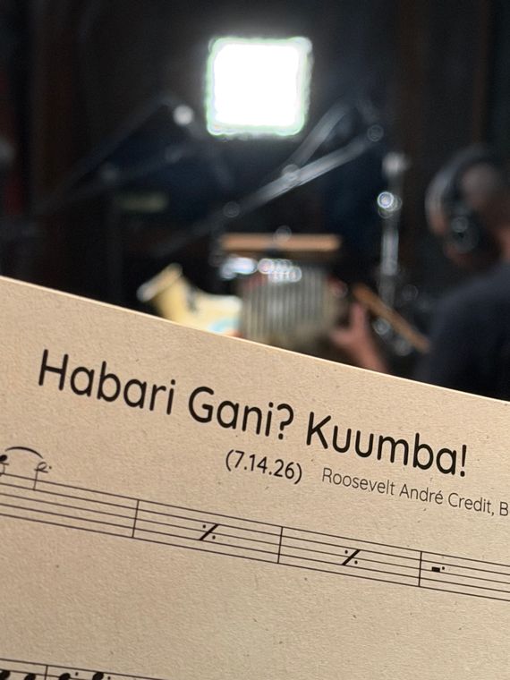The Habari Gani? Kuumba! score, with the percussion setup out of focus behind it.