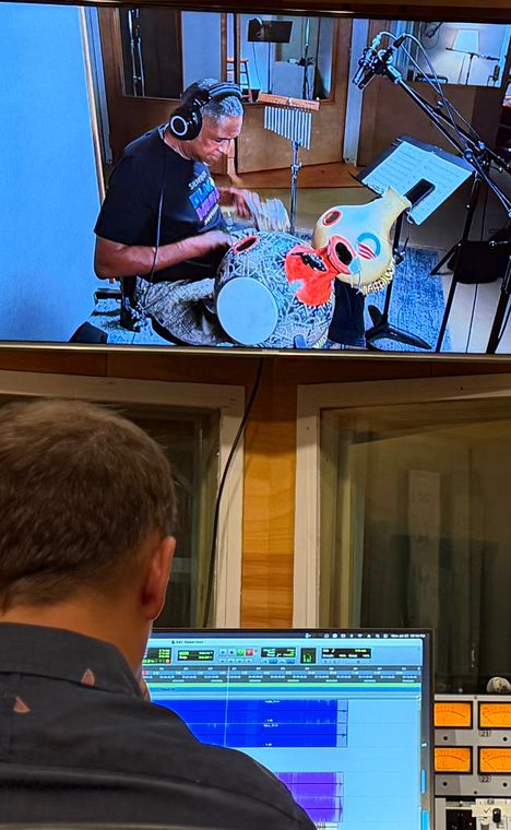 An engineer at the session screen while the monitor shows Ronnie Burrage on percussion.