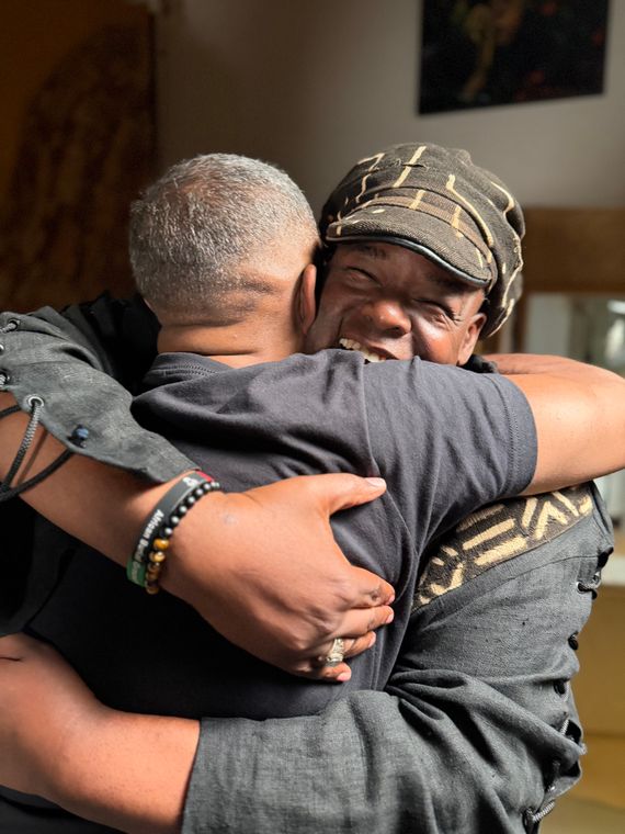 Two musicians sharing a hug in the studio.