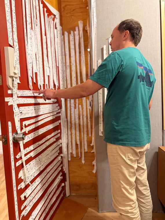 An engineer pointing to the hand-labelled tape strips covering a studio door.