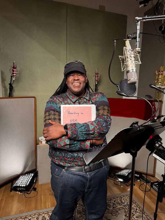 Roosevelt Andr&eacute; Credit in the vocal booth, holding the Holiday Survival Kit book.