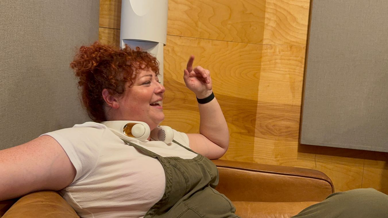 A singer with curly red hair laughing on the leather couch in the studio lounge.