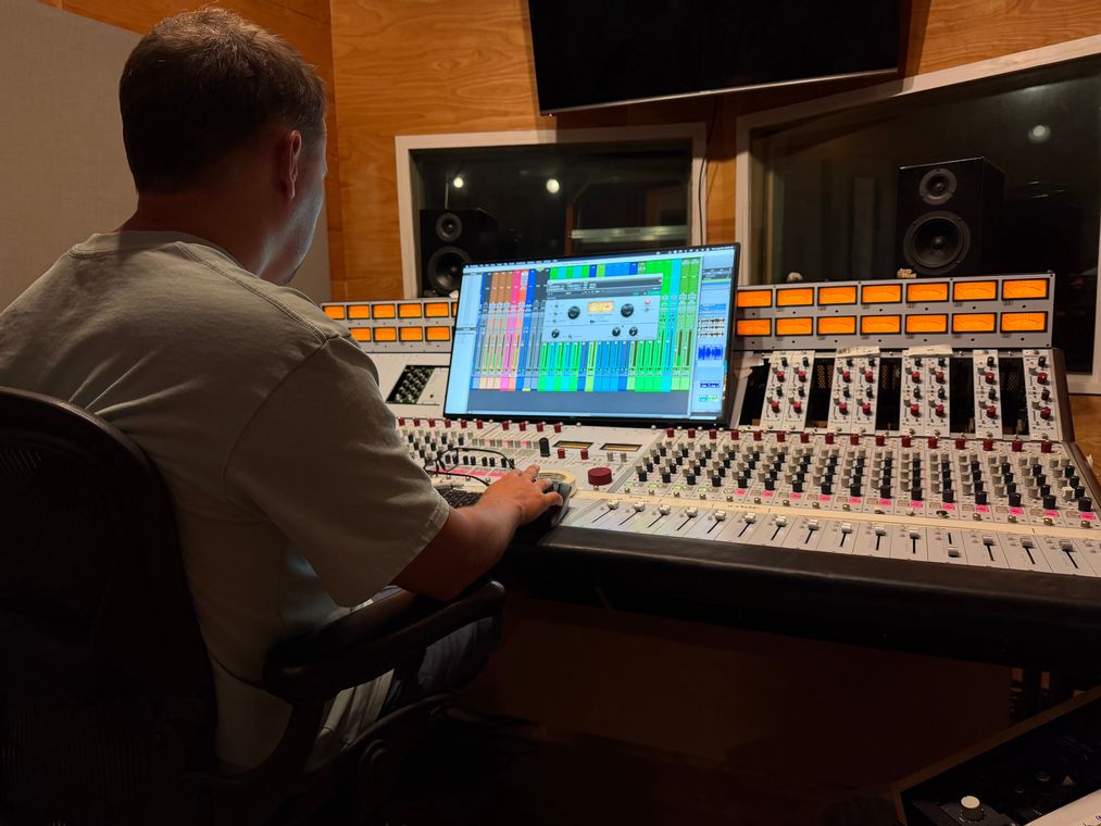 An engineer at the mixing console with the session on screen.