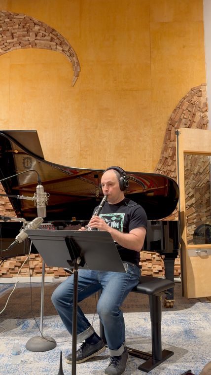 Dennis Lichtman playing clarinet beside the grand piano.