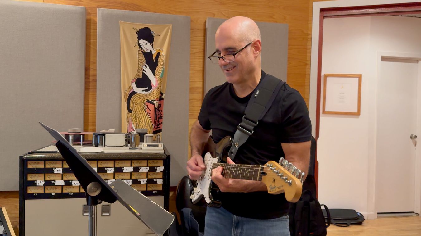 Tony Romano smiling as he plays electric guitar.